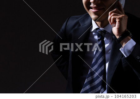 黒背景で詐欺電話をかける男性ビジネスマン 104165203