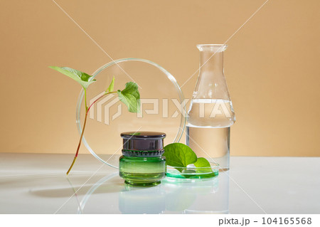 Unbranded jar decorated with petri dish and conical flask with few fish mint. Container packaging of skin care branding extracted from Fish mint (Houttuynia cordata) 104165568
