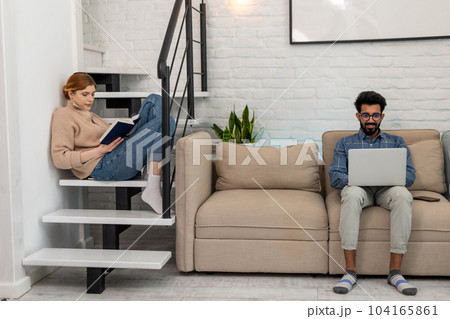 Brunette bearded young man with a laptoop sitting on the sofa Brunette bearded young man with a laptoop sitting on the sofa 104165861