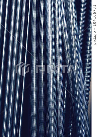 Construction warehouse. Toned image. Threaded rods are also called studs. Galvanized threads run along the entire length of the rod. They are used with a metal spacer 104166731