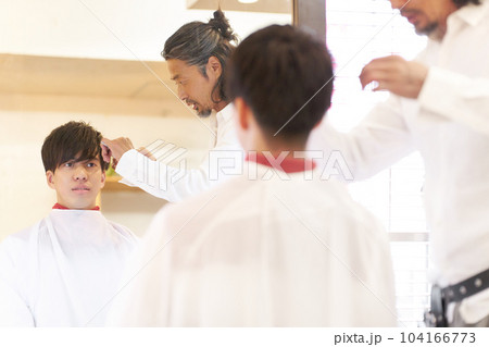 若い男性客とその髪をカットするベテランのヘアスタイリスト 104166773