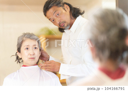 ヘアサロンにて施術中のヘアスタイリストと女性客 ヘアサロンにて施術中のヘアスタイリストと女性客 104166791