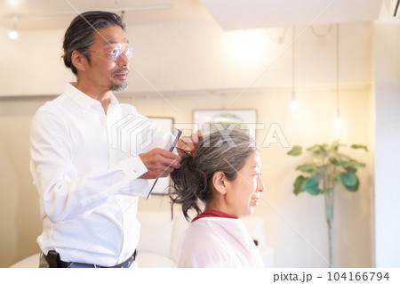 ヘアサロンにて施術中のヘアスタイリストと女性客 104166794