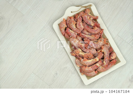 Chicken necks on a ceramic board on wood background. Chicken raw meats. Top view. Chicken necks on a ceramic board on wood background. Chicken raw meats. Top view. 104167184
