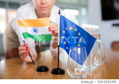 Employee of delegation prepares negotiating table - sets up flag of European Union and India 104168299