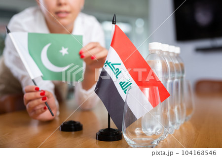Unrecognizable girl sets midget flags of Iraq and Pakistan before international negotiations Unrecognizable girl sets midget flags of Iraq and Pakistan before international negotiations 104168546