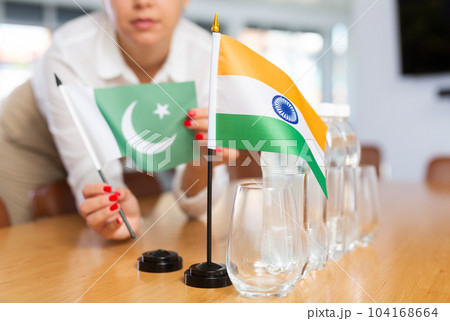 Employee of delegation prepares negotiating table - sets up flag of India and Pakistan 104168664