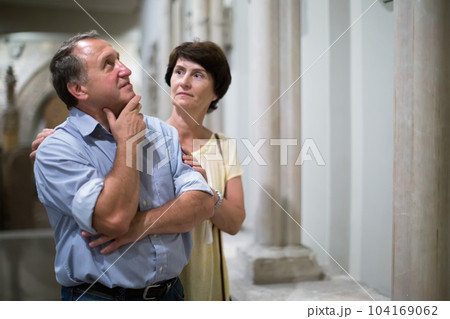 mature men and women collector evaluates the exhibition in museum 104169062