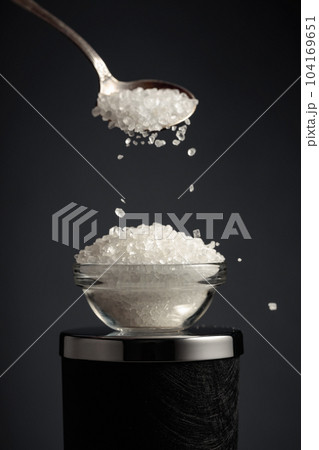 Sea salt is poured into a small bowl. Sea salt is poured into a small bowl. 104169651