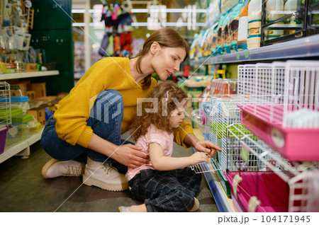 Smiling woman with her daughter choosing hamster or other rodent at pet shop Smiling woman with her daughter choosing hamster or other rodent at pet shop 104171945