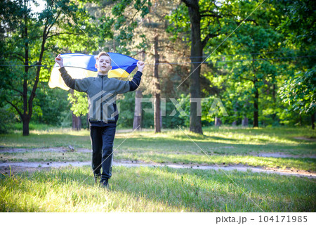 Pray for Ukraine. boy with Ukrainian flag running the summer par Pray for Ukraine. boy with Ukrainian flag running the summer par 104171985