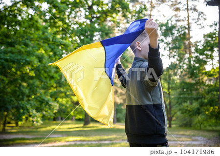 Pray for Ukraine. boy with Ukrainian flag running the summer park. Little kid waving national flag praying for peace. Happy child celebrating Independence Day 104171986