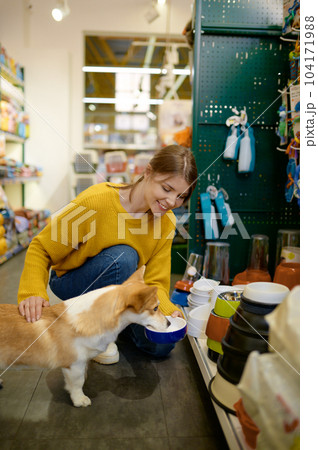 Young woman offering her lovely dog to choose new feed bowl 104171988