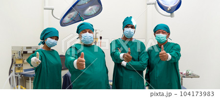 Group of doctor and nurse in surgical green gown uniform stand confidently with finger thumb up before performing an operation in the operating room. 104173983