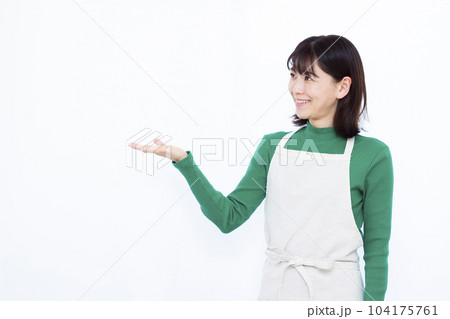 白い背景の前で紹介をしているエプロン姿の30代主婦 104175761
