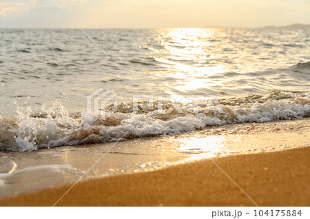Seawater soft wave crashing on sandy beach seaside in summer on sunset time. summer vacation activity background concept.. 104175884
