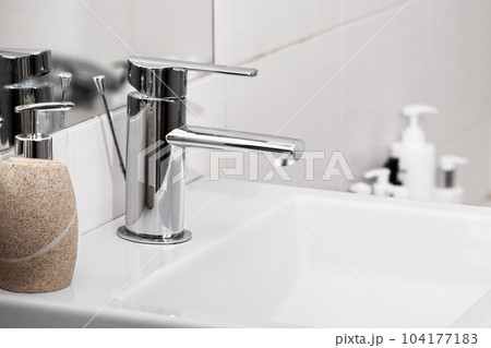 Sink and faucet in modern white bathroom. Chrome faucet in bathroom interior. Sink and faucet in modern white bathroom. Chrome faucet in bathroom interior. 104177183