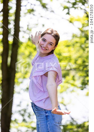 Young woman with her arms wide spread is enjoying in the sunny summer day in the forest between the Young woman with her arms wide spread is enjoying in the sunny summer day in the forest between the 104178850