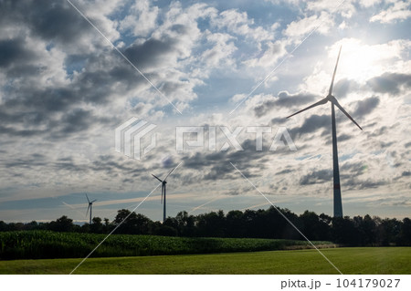 Silhouettes of wind turbines on a green agrarian farm field against dramatic clouds before the storm 104179027