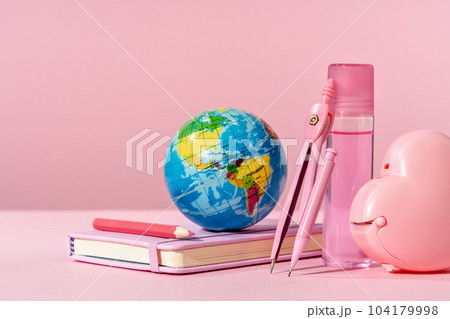 pink stationery with blue toy globe on pink background with diary or copybook. Office or school stationery. Back to school. Drawing writing or storyteling concept. notes taking. meeting 104179998