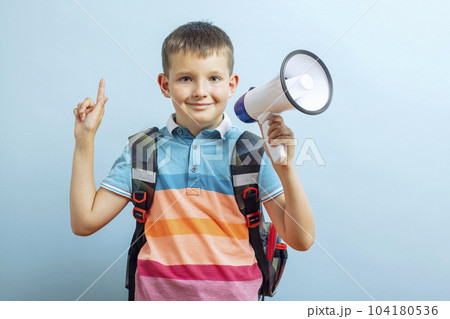 Little school boy shouting through a megaphone on blue background 104180536