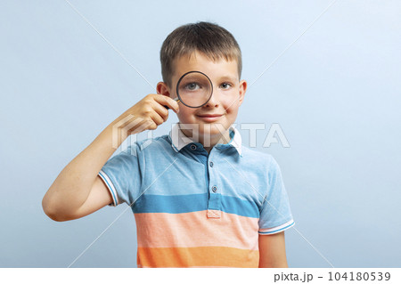 Schoolboy in casual clothes looks through magnifying glass Schoolboy in casual clothes looks through magnifying glass 104180539