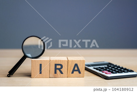 Wooden blocks with the word IRA - individual retirement account. Tax-advantaged account that individuals use to save and invest for retirement. Business and finance concept Wooden blocks with the word IRA - individual retirement account. Tax-advantaged account that individuals use to save and invest for retirement. Business and finance concept 104180912