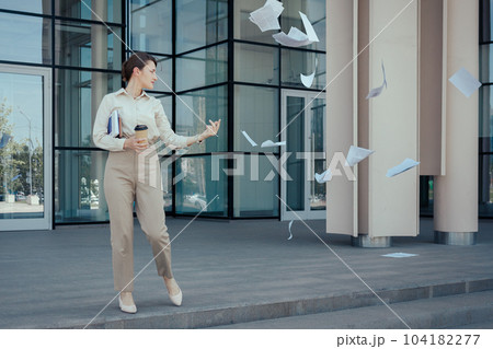 Business woman runs out of an office building throwing paperwork around. How to freeze current affairs before vacation or weekend, time management problems 104182277
