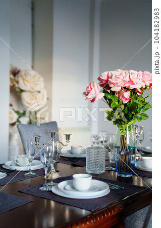 A beautiful table served with dishes and a bouquet of roses. A beautiful table served with dishes and a bouquet of roses. 104182983