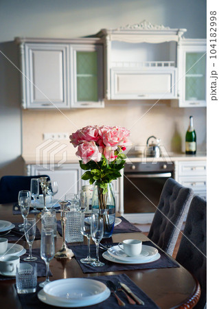 table with dishes and bouquet of roses in the bright kitchen of the living room table with dishes and bouquet of roses in the bright kitchen of the living room 104182998