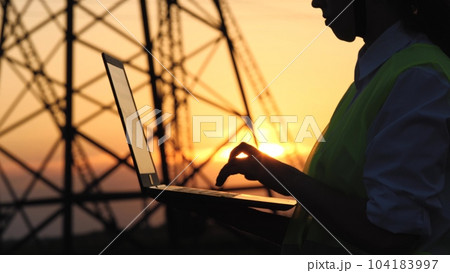 silhouette electrical engineer, work computer tablet sunset, electric tower, digital hand, engineer with tablet works near electric poles sunset, business partnership, with high voltage pylon 104183997