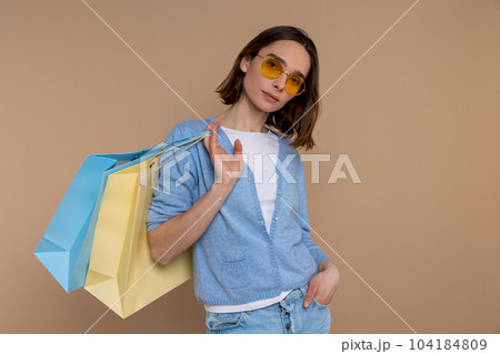Confident fashion woman in casual clothing holding shopping bags spending time in mall Confident fashion woman in casual clothing holding shopping bags spending time in mall 104184809