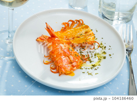 Split fried prawns with parsley and spice on a white plate 104186460