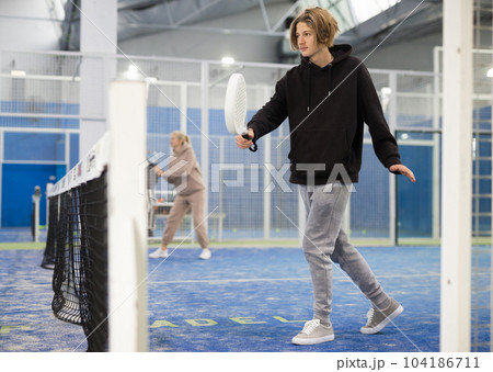 Teenage guy playing paddle tennis on padel court 104186711