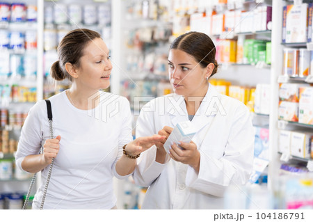Woman pharmacist helping woman customer to choose remedy in pharmacy Woman pharmacist helping woman customer to choose remedy in pharmacy 104186791
