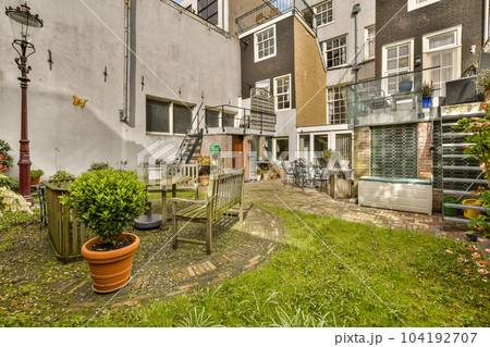 a back yard with some plants and pots on the ground in front of an apartment building that is being used as a garden 104192707