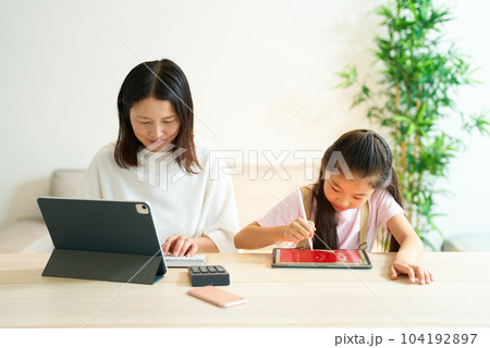 タブレットPCを使って仕事をする女性と遊ぶ女の子 タブレットPCを使って仕事をする女性と遊ぶ女の子 104192897