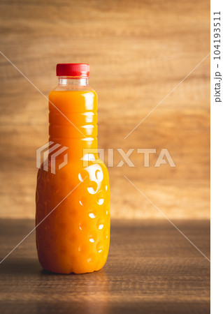 A bottle of fruit juice. Orange juice on wooden table. A bottle of fruit juice. Orange juice on wooden table. 104193511
