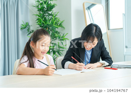 勉強する女の子とサポートするスーツ姿の女性 勉強する女の子とサポートするスーツ姿の女性 104194767