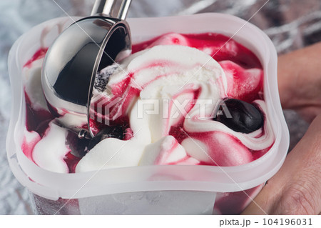Cherry ice cream. An ice cream spoon is inserted into an ice cream with a cherry in a cup. Ice cream closeup. The concept of treats for children and adults. 104196031