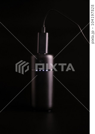 powerbank black on a black background, usb cable, plug, light and reflection powerbank black on a black background, usb cable, plug, light and reflection 104197828