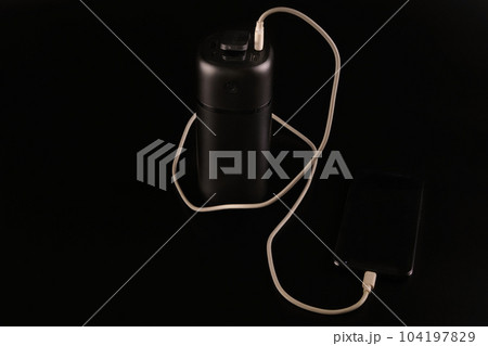powerbank black on a black background, usb cable, smartphone, plug, light and reflection powerbank black on a black background, usb cable, smartphone, plug, light and reflection 104197829
