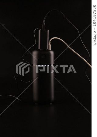 powerbank black on a black background, usb cables, plug, light and reflection powerbank black on a black background, usb cables, plug, light and reflection 104197830