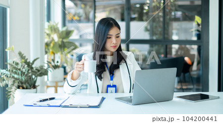 Asian businesswoman smiling happily with a new morning holding a cup of coffee lightly sipping coffee professional woman in size working in the office 104200441