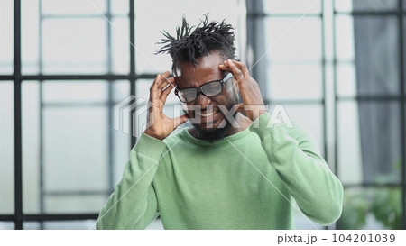 african american man in a green shirt holding his hands behind his head 104201039