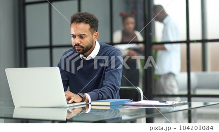 African businessman working on a laptop in an office African businessman working on a laptop in an office 104201084