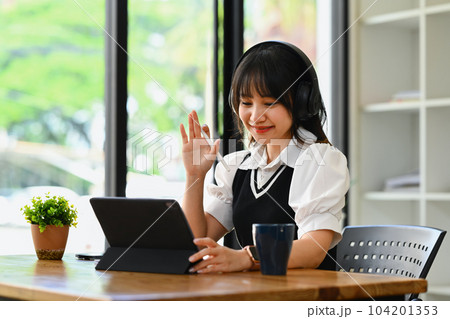 Smiling asian female student wearing headphone learning language, watching online webinar on laptop 104201353