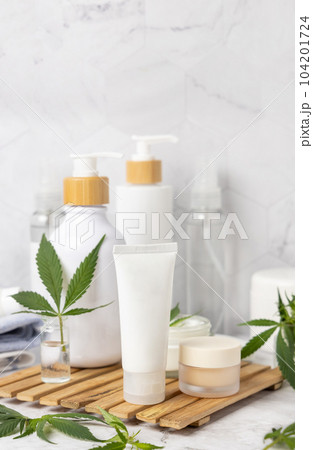 White blank cream tube near green cannabis leaves close up, CBD cosmetic mockup 104201724