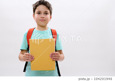 Confident portrait of a Caucasian teenager boy, happy handsome school child 11-13 years old with backpack, holding workbooks and cutely smiling looking at camera, isolated over white studio background Confident portrait of a Caucasian teenager boy, happy handsome school child 11-13 years old with backpack, holding workbooks and cutely smiling looking at camera, isolated over white studio background 104201948