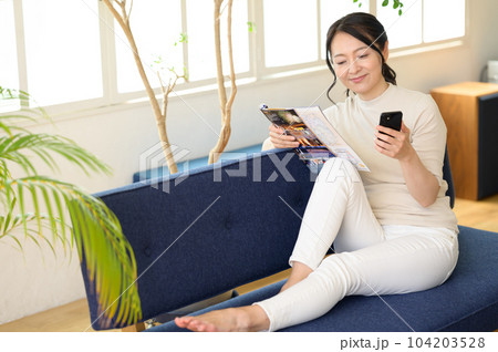 スマホを片手にパンフレットを見るミドル女性 スマホを片手にパンフレットを見るミドル女性 104203528